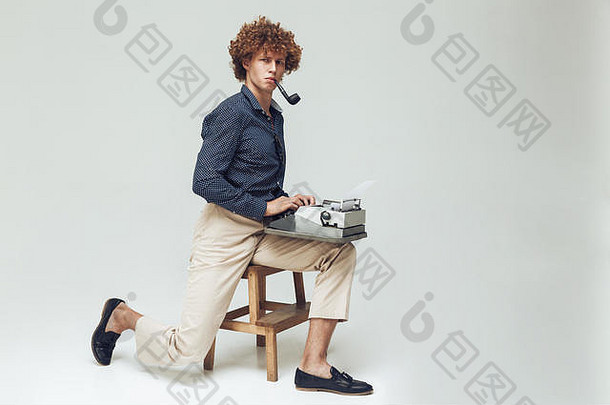 图像年轻的复古的男人。穿着衬衫坐着摆姿势孤立的相机管持有打字机