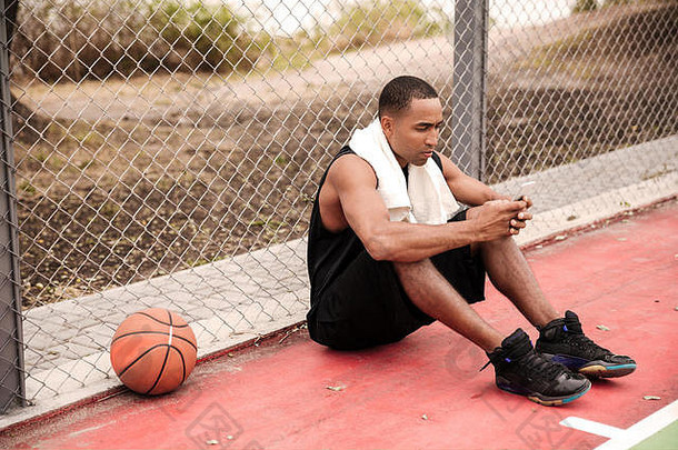图像年轻的累了非洲<strong>篮球</strong>球员坐着公园毛巾<strong>篮球</strong>聊天电话