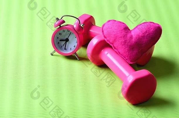 哑铃粉红色的颜色报警时钟软玩具心绿色背景复制空间心装饰杠铃瑜伽席早....锻炼概念爱体育早期培训