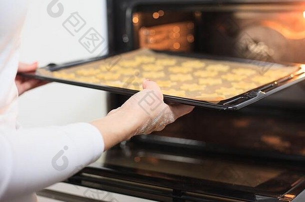 年轻的手给烘焙表姜热烤箱食物概念