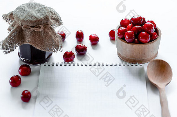 红色的成熟的<strong>樱桃</strong>小时Jar木勺子笔记本白色背景平躺食物概念