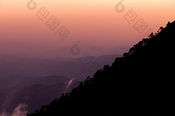 轮廓山坡塔贾穆尔科树前面橙色紫色的日落