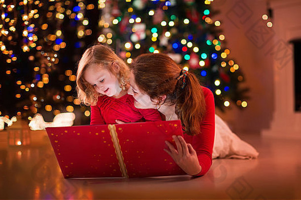 妈妈。女儿读书壁炉圣诞节夏娃家庭孩子庆祝圣诞节装饰房间树