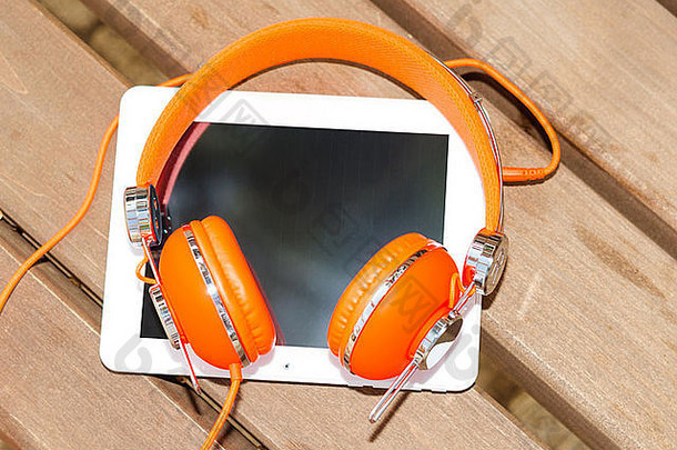 白色平板电脑橙色耳机木板凳上