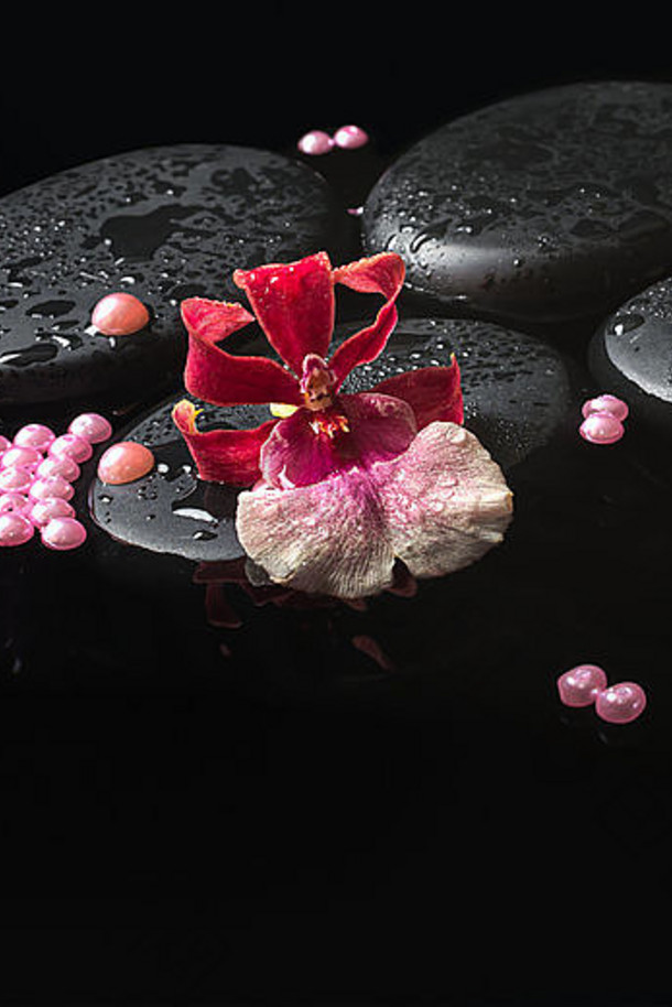 水疗中心设置兰花威尔士花Zen石头滴珍珠珠子红色的蜡烛反射水特写镜头
