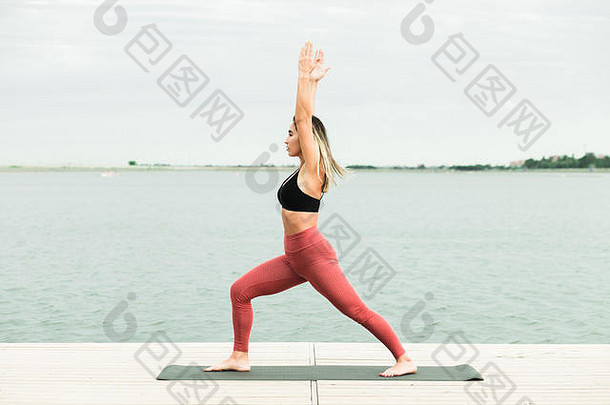 年轻的女孩瑜伽在户外码头湖她是穿黑色的前红色的紧身裤