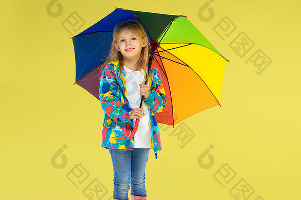 完整的长度肖像明亮的时尚女孩雨衣持有伞彩虹颜色黄色的工作室背景秋天春天时尚孩子们可爱的时尚的金发女郎女孩
