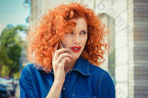 愤怒的沮丧红色的卷曲的头发女人会说话的移动电话站