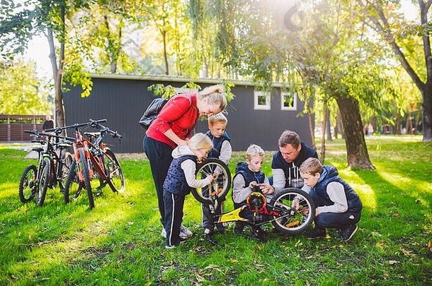 主题团队合作友好的家庭户外活动父母教孩子们解决问题父亲显示修复自行车