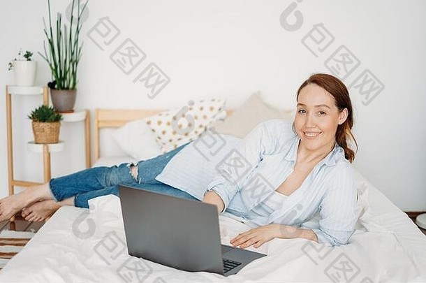 工作年轻的成人微笑浅黑肤色的女人女人自由职业者休闲衣服移动PC工作首页明亮的室内