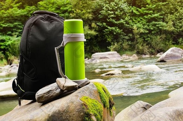 照片旅行背包热水瓶瓶站森林河岩石流背景