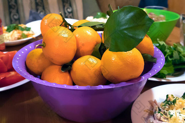 多汁的成熟的橘子新鲜的绿色叶紫罗兰色的塑料碗乡村聚会，派对表格