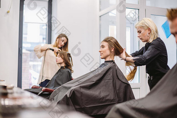 美丽的女人梳理湿头发设计师刷牙女人头发沙龙理发师服务客户专业年轻的理发师工作梳子