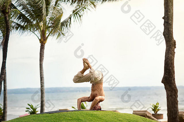 肌肉发达的健康的男人。瑜伽热带自然前面海洋