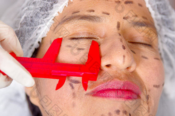 特写镜头女士脸准备化妆品手术行画皮肤医生测量工具