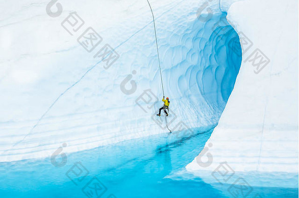 男人。黄色的夹克橙色头盔催巨大的蓝色的冰洞穴淹没了蓝色的池前奴斯冰川远程阿拉斯加