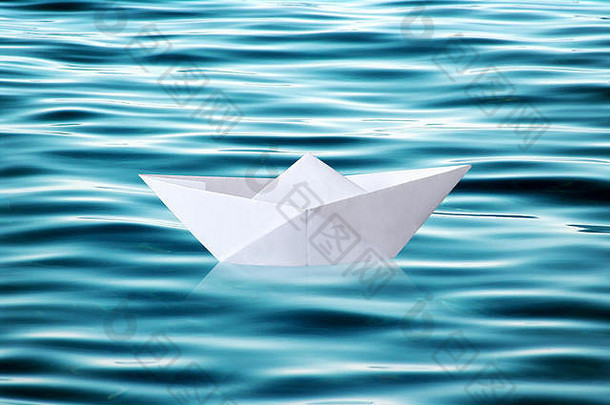 小白色折叠纸折纸船浮动波及蓝色的水