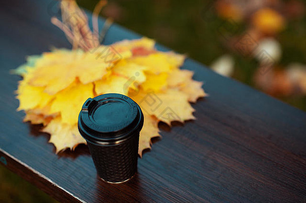 秋天特写镜头黄色的叶子杯咖啡板凳上在户外秋天公园