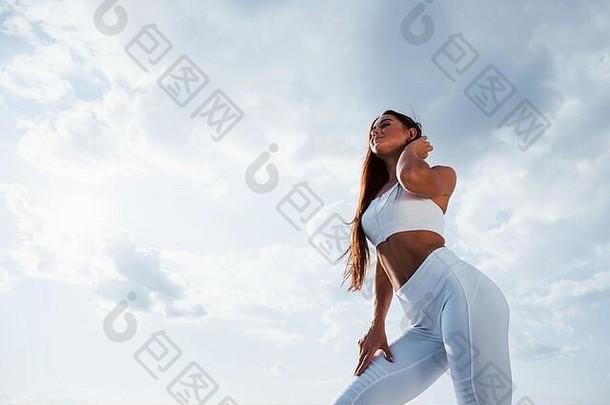 浅黑肤色的女人健身女人站在户外白色运动型衣服多云的天空白天