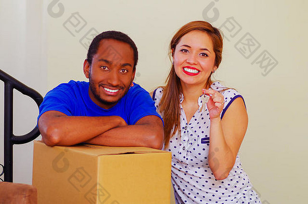迷人的跨种族夫妇微笑相机倾斜纸板盒子移动概念