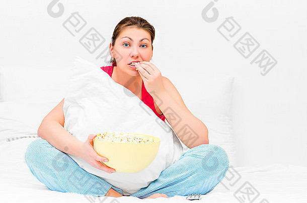 浅黑肤色的女人用心看电视吃爆米花