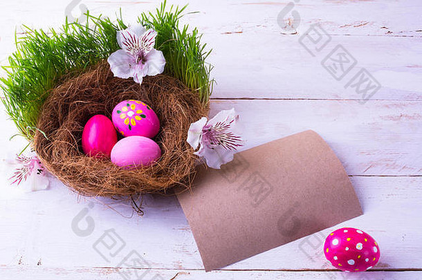 粉红色的复活节鸡蛋巢白色花绿色新鲜的草白色木背景自然原色