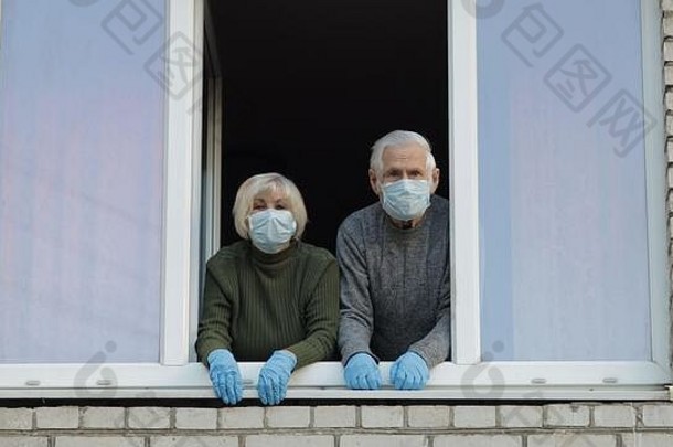 祖父祖母窗口保护面具孤立的首页检疫病毒爆发老男人。女人科维德流感大流行冠状病毒预防社会距离