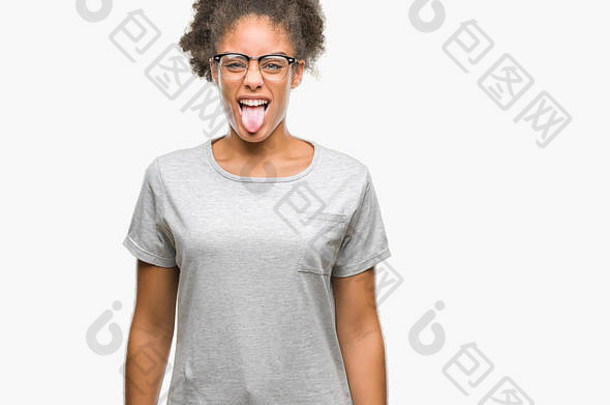 年轻的非洲式发型美国女人穿眼镜孤立的背景坚持舌头快乐有趣的表达式情感概念