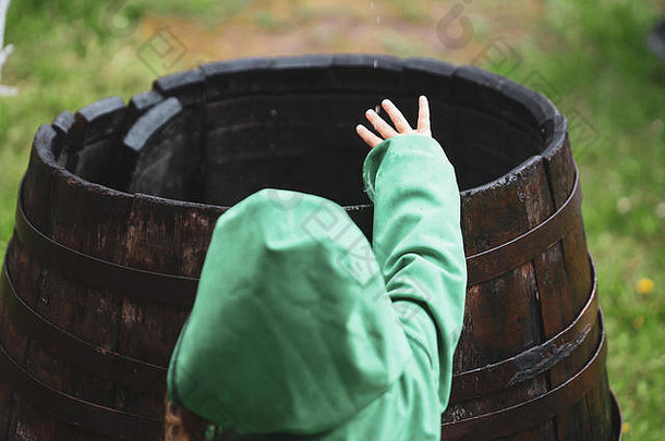女孩绿色连身裤玩雨水木桶院子里房子农村罗马尼亚多雨的一天