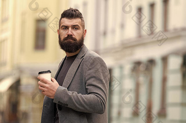 sip咖啡城市生活方式商人培养外观享受咖啡打破业务中心城市背景放松充电男人。有胡子的赶时髦的人喝咖啡纸杯