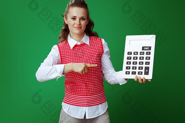 快乐年轻的学生灰色牛仔裤粉红色的无袖衬衫指出大白色计算器绿色背景<strong>财务</strong>状况<strong>支出</strong>