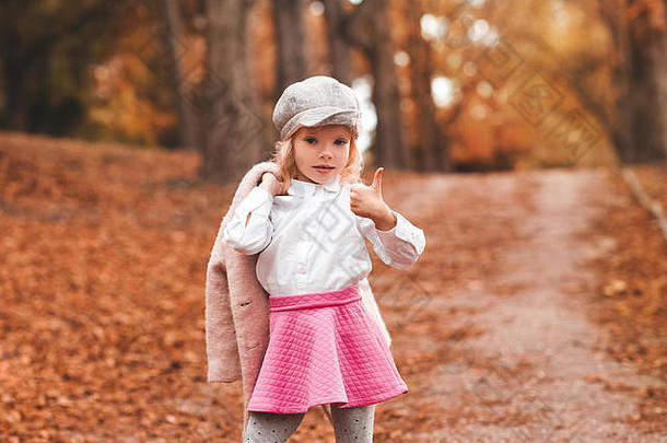 时尚的<strong>孩子</strong>女孩一年穿时尚的秋天衣服摆姿势自然背景公园相机拇指
