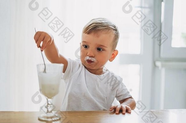 <strong>迷人</strong>的集中婴儿男孩吃<strong>酸</strong>奶玻璃明亮的厨房首页