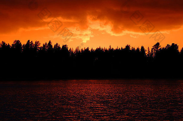 多云的天空燃烧红色的日落黑色的森林黑暗红色的水带来了世界末日的大气