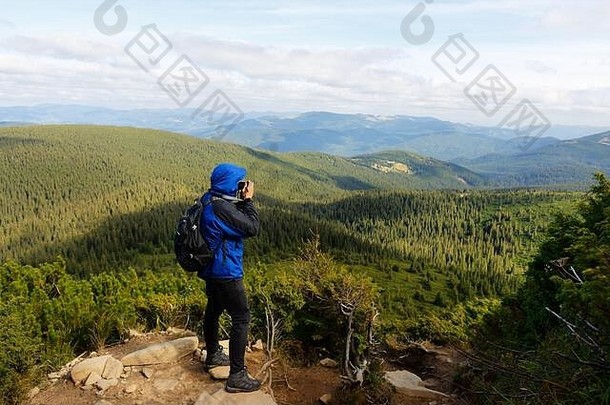 年轻的专业旅行者男人。数码单反相机相机拍摄户外神奇的山景观徒步旅行者站岩石高峰会