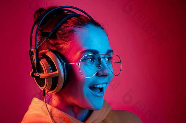 时尚漂亮的女人耳机听音乐红色的霓虹灯背景工作室