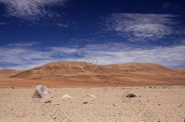 视图多石的贫瘠的荒地红色的山形成对比蓝色的天空卷云云阿塔卡马沙漠智利