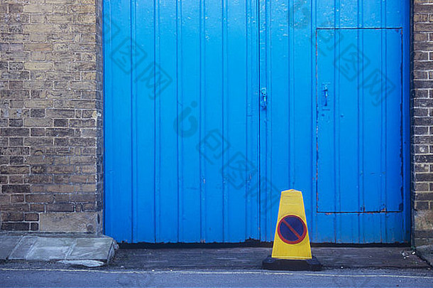 黄色的停车锥前面蓝色的画木双盖茨行人通过插入玷污了黄色的brickwalls