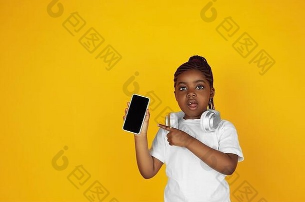 指出电话听音乐非裔美国人女孩的肖像黄色的工作室背景快乐的孩子概念人类情绪面部表达式销售Copyspace可爱的