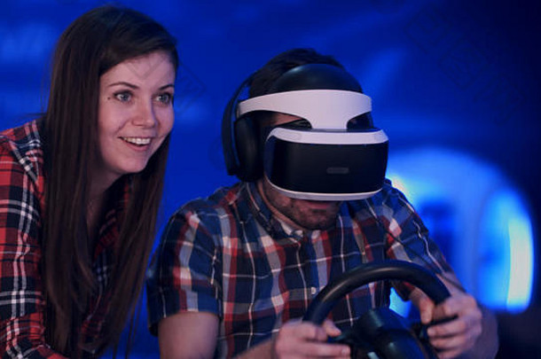 漂亮的微笑女孩看的男朋友玩<strong>赛车视频</strong>游戏虚拟现实耳机