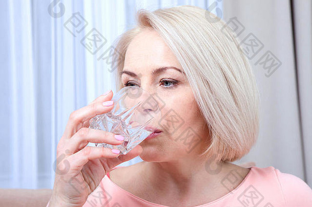 肖像美丽的中间岁的女人喝水早....