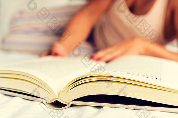 年轻的高加索人女人睡衣阅读书床上