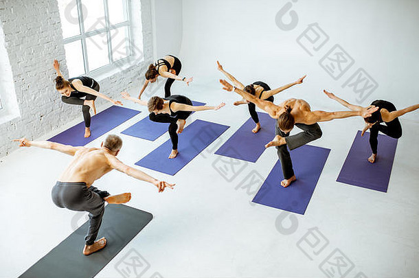 集团年轻的人练习瑜伽有经验的高级教练白色宽敞的工作室