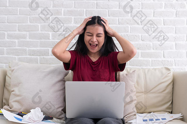 亚洲女人自由职业者喊压力情感工作移动PC文书工作沙发生活房间房子工作首页概念