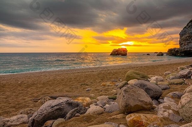 粗沙子海滩石头色彩斑斓的日落平静海