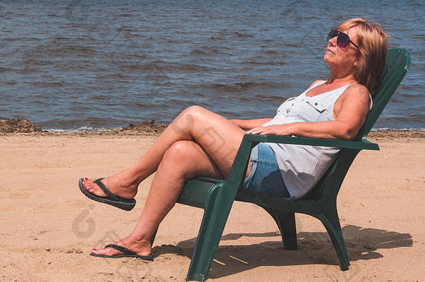 退休女人假期坐着海滩北美狗鱼湖魁北克加拿大