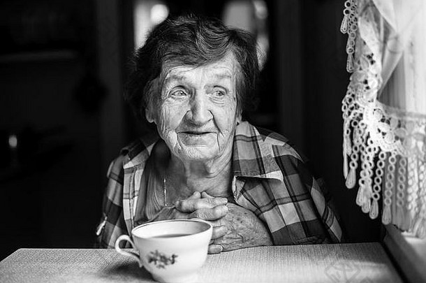 上了年纪的女人喝茶坐着表格房子黑白肖像