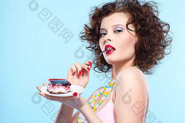 肖像美丽的卷曲的浅黑肤色的女人女孩吃蛋糕