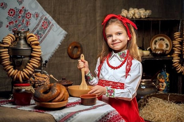 女孩穿红色的头巾观赏衬衫坐着表格完整的食物大茶壶庆祝maslenitsa