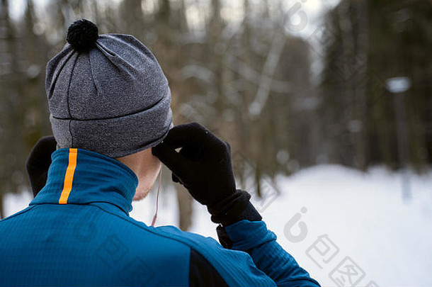 肖像跑步者回来穿耳机准备运行冬天森林